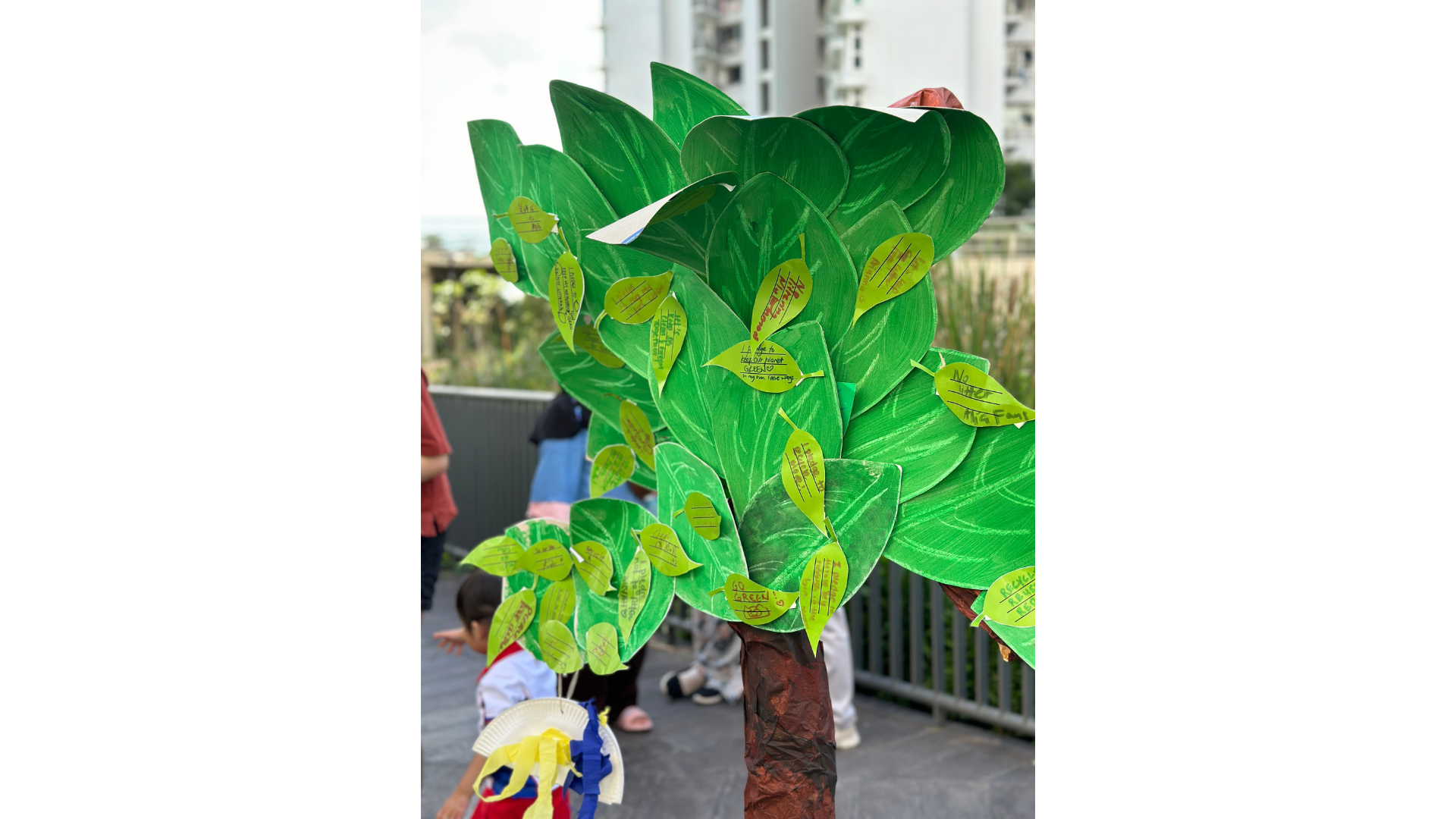 a paper tree filled with pledges to protect the environment by children and their parents